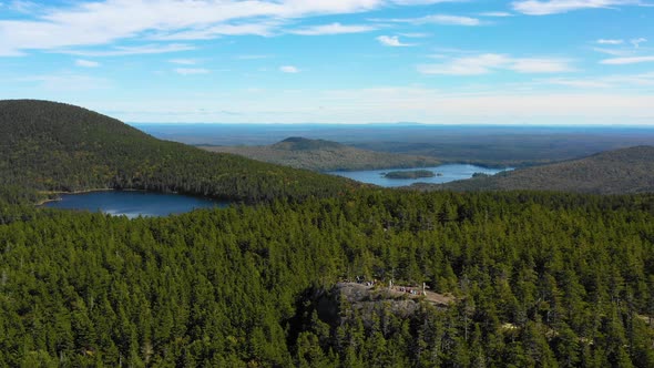 Aerial drone establishing shot over the vast green and autumn colored forest with blue lakes dotting