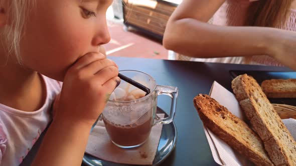 Child Makes Bubbles with Straw in a Glass