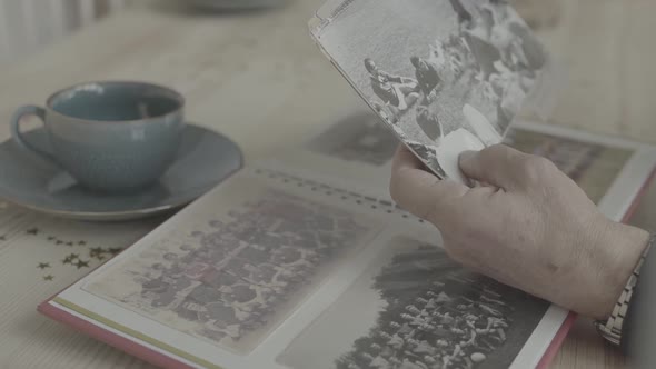 Old Woman Hands Pointing at Young People on Black White Photograph in Family Photo Album on Wood