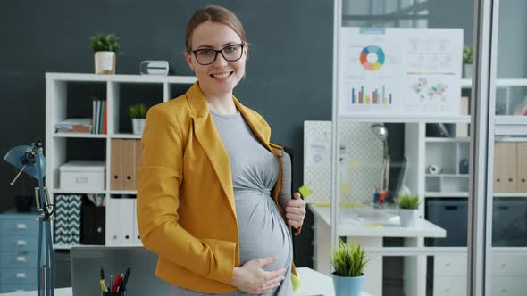 Portrait of Successful Pregnant Lady Standing in Workplace Smiling Looking at Camera