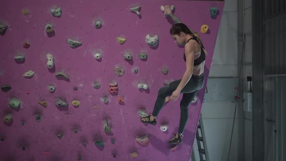 Fitness Woman Finishing Her Training in Artificial Rock Wall Looks Tired and Satisfied