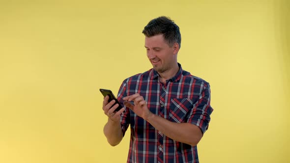 Cheerful Young Man Is Very Delighted with Something Looking on Smartphone