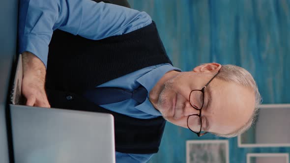 Vertical Video Retired Manager Sitting at Desk in Front of Camera Smiling