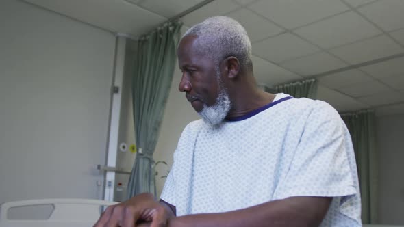 African american male patient looking at window holding cane in hospital room