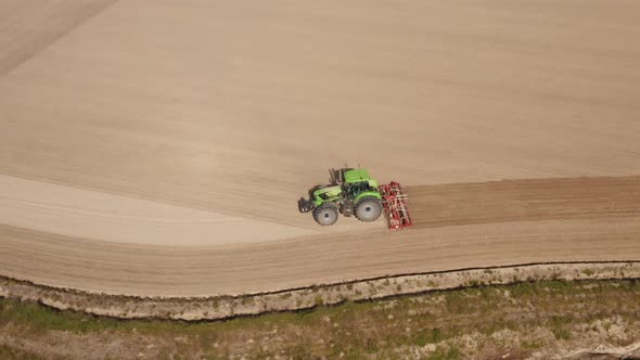 Aerial view of a tractor plowing a field in Lomellina, Po Valley, Italy.