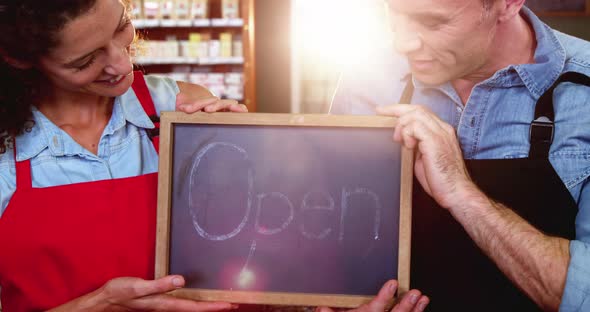 Staff holding a open sign slate in supermarket