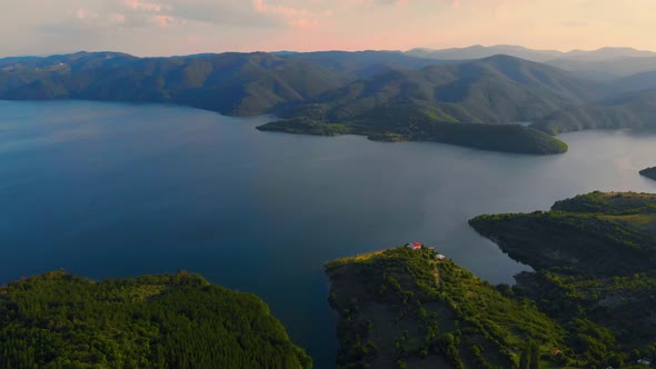 Flying high toward a lake with a horizon view of a wrinkled mountain terrain.