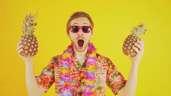 Portrait of happy young man with hawaiian shirt and two pineapples slow motion