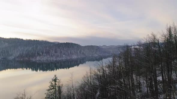 Revealing shot of calm winter lake with reflection during sunset