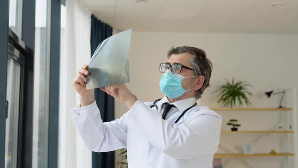 Senior Doctor 50s Examining an Xray of the Lungs of a Covid 19 Patient