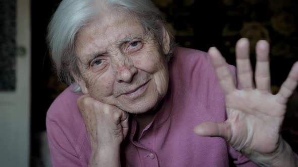 Old Woman Waves And Speaks To Camera While Communicating Remotely On Isolation