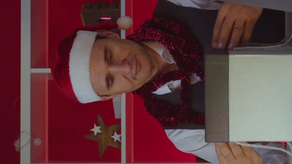 Vertical Shot 40s Businessman in Santa Hat Opens Magic Gift Box in Christmas Decorated Office