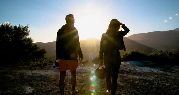 Travelling couple walking towards the sunset in the mountains, slow motion.