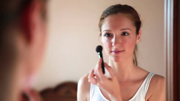 Beautiful Woman at the Mirror Applying Make Up