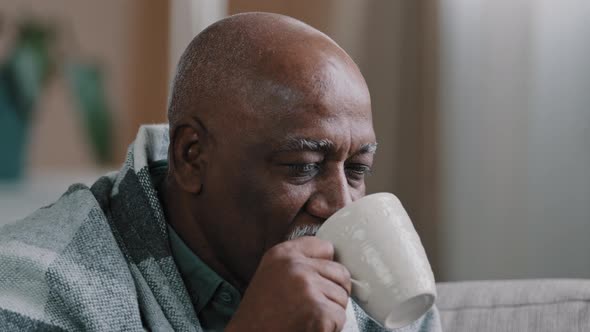 Close Up Ill Sick Elderly African American Man Covered with Warm Blanket Sitting on Couch in Living