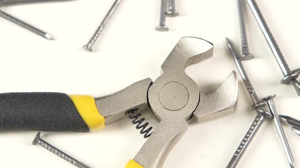 Wire Cutters with Yellow, Gray Handle on White Among Nails, Rotation, Close Up