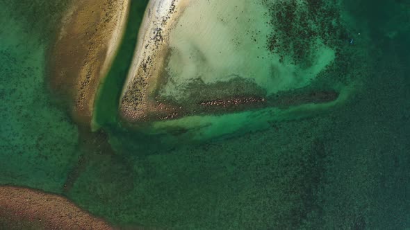 Wide birds eye travel shot of a white paradise beach and turquoise sea background in vibrant 4K