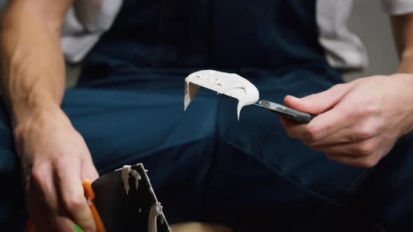 Man Builder Putting Wall Plaster on Spatulas Closeup