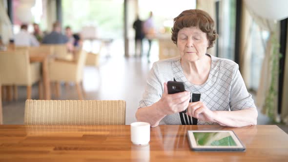 Senior Woman Using Phone While Thinking At The Coffee Shop