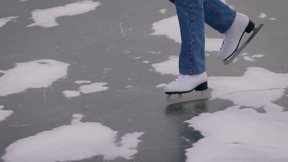 Ice Skating on a Frozen Lake. In the Frame, Close-up of Legs in Jeans and White Skates.