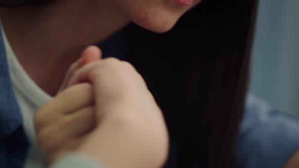 Mother Holding Kid Hand Sitting at Bedside Closeup