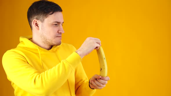 Close Up of Young Man Peeling Banana on Yellow Background