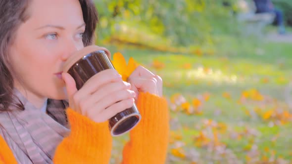 Beautiful Woman Enjoying Autumn Park and Drinking Hot Coffee