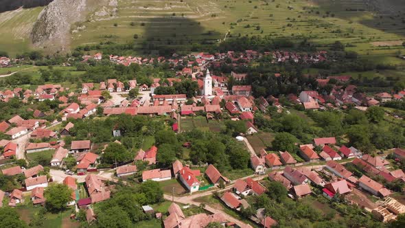 Tilt up reveal of the town of Rimetea Transylvania Romania and the mountains.