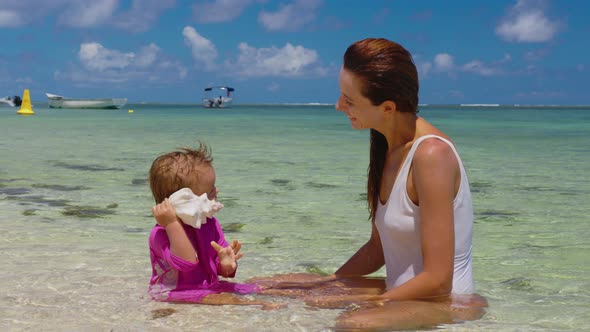 Mom and Her Daughter are Playing in the Clear Water on the Shore of the Indian Ocean