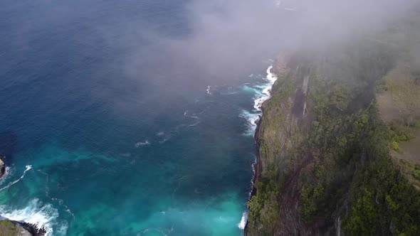 Wonderful aerial view flight hover drone shot in over clouds high in skyKelingking Beach at Nusa Pe