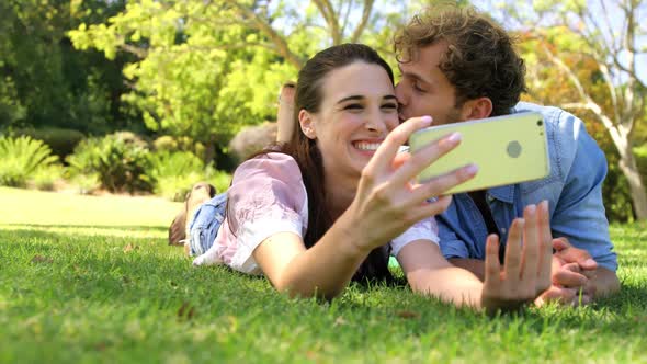 A couple lying on the grass taking a selfie