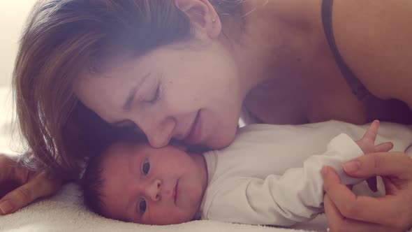 Newborn baby boy and his mother at home. Close-up portrait of the infant