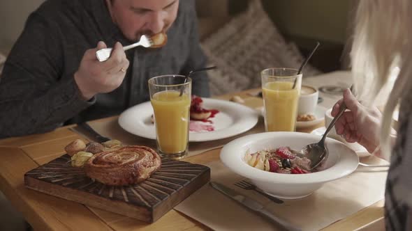 Married Couple Is Having Breakfast in a Cafe Eating Porridge and Pancakes