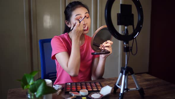Beauty blogger with makeup palette recording video
