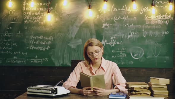 Female University Professor Preparing for Class. Female Teacher Sitting in the Classroom While