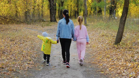 Beautiful Young Woman with Two Children Walking in Forest