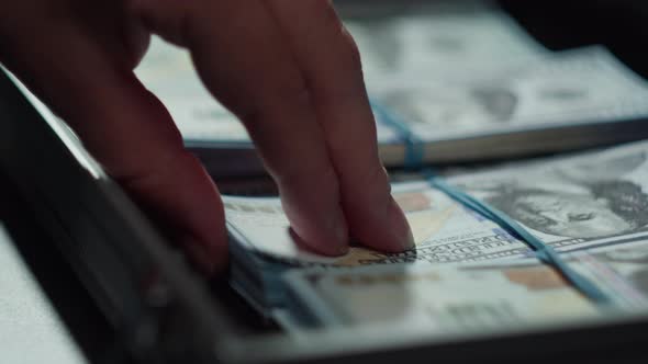 Counting American Hundred Dollar Banknotes Putting Money in Metallic Suitcase