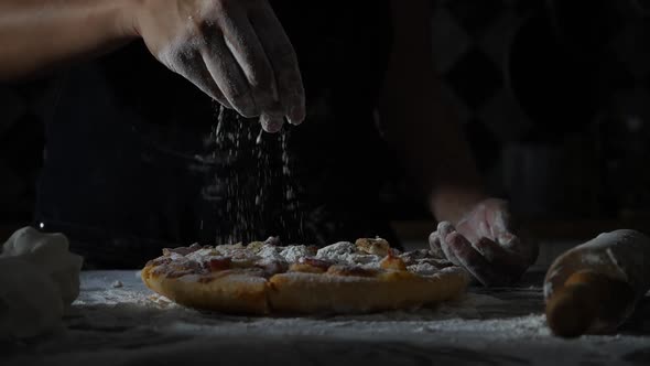 Slow motion of woman hands sifting flour on pizza