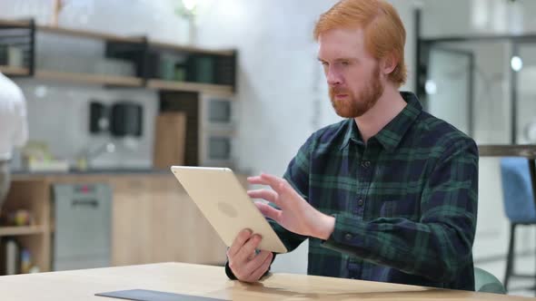 Young Beard Redhead Man Using Digital Tablet in Cafe