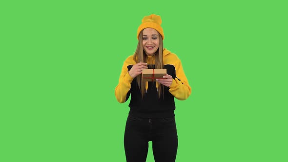 Modern Girl in Yellow Hat Is Opening the Gift, Very Surprised and Rejoicing. Green Screen