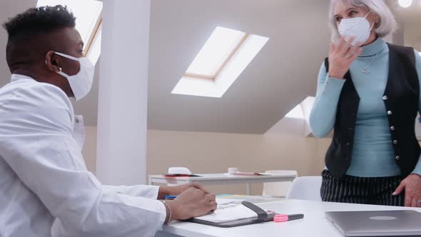 Elderly Woman Comes on Consultation with Doctor Coughing and Wearing Mask