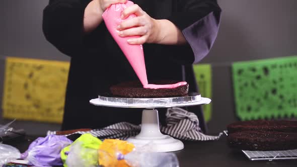Time lapse. Step by step. Baker assembling a chocolate cake with bright colorful buttercream frostin