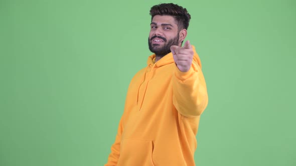 Happy Young Overweight Bearded Indian Man Pointing at Camera