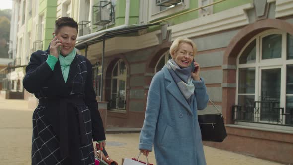 Two Happy Mature Women Talking Using Smartphone Outdoors