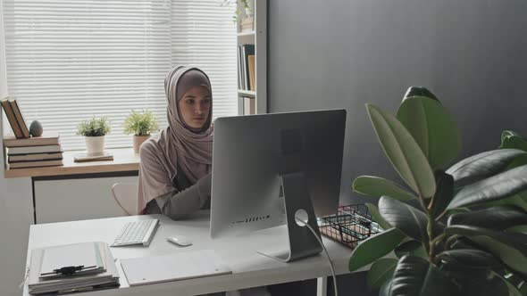 Muslim Woman Discussing Document on Video Call on Computer