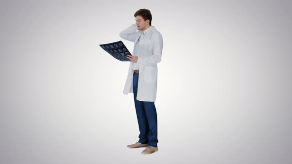 Frustrated Male Doctor Examining Computed Tomography Scan of Brain on Gradient Background