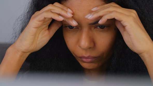 Stressed African woman lookin in laptop screen looking for problem solution