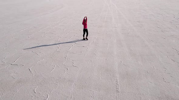 Aerial shot of an Asian woman hiking across the Bonneville Salt Flats flats