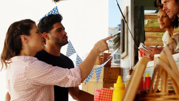 Smiling waiter taking order from couple