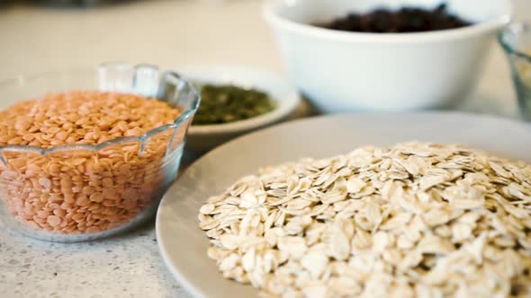 Lentils, oats, seeds, beans arranged in bowls on bench, slide close-up low-angle